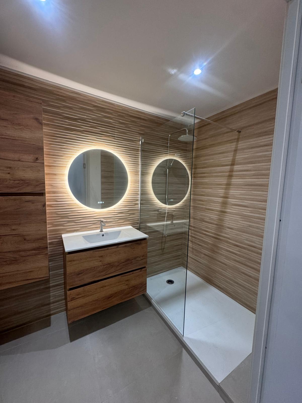 Salle de bain avec douche italienne, carrelage imitation bois et miroirs ronds LED – Martigues